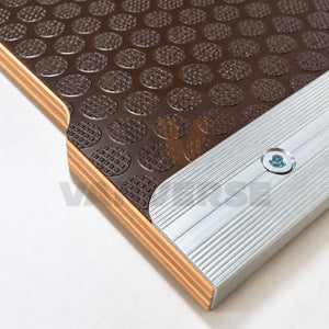Detalle del tablero fenólico marrón con textura antideslizante y perfil de aluminio fijado con tornillo.